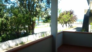 A covered balcony with a view of trees and a distant building. - Seaside House with Private Entrance, Steps from Beach and Station (Termini)