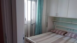 A bedroom with a bed, a window with curtains, and white cabinets. - Seaside House with Private Entrance, Steps from Beach and Station (Termini)