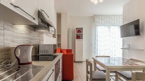 Une cuisine moderne avec des meubles blancs, un four à micro-ondes, une bouilloire et un coin repas comprenant une table et des chaises.