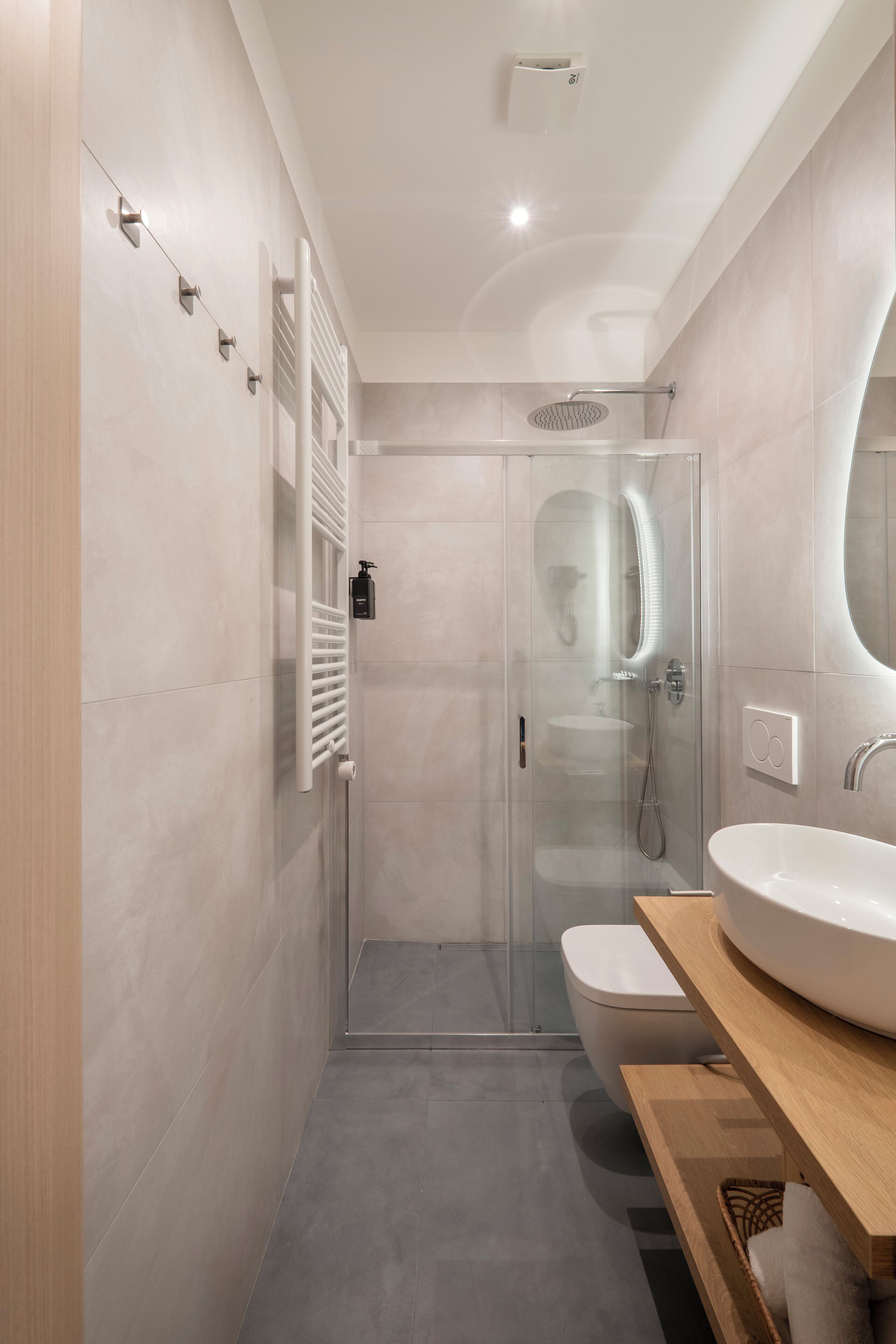 A modern bathroom with a glass-enclosed shower, a white sink, and a wooden vanity.