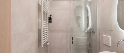 A modern bathroom with a glass-enclosed shower, a white sink, and a wooden vanity.