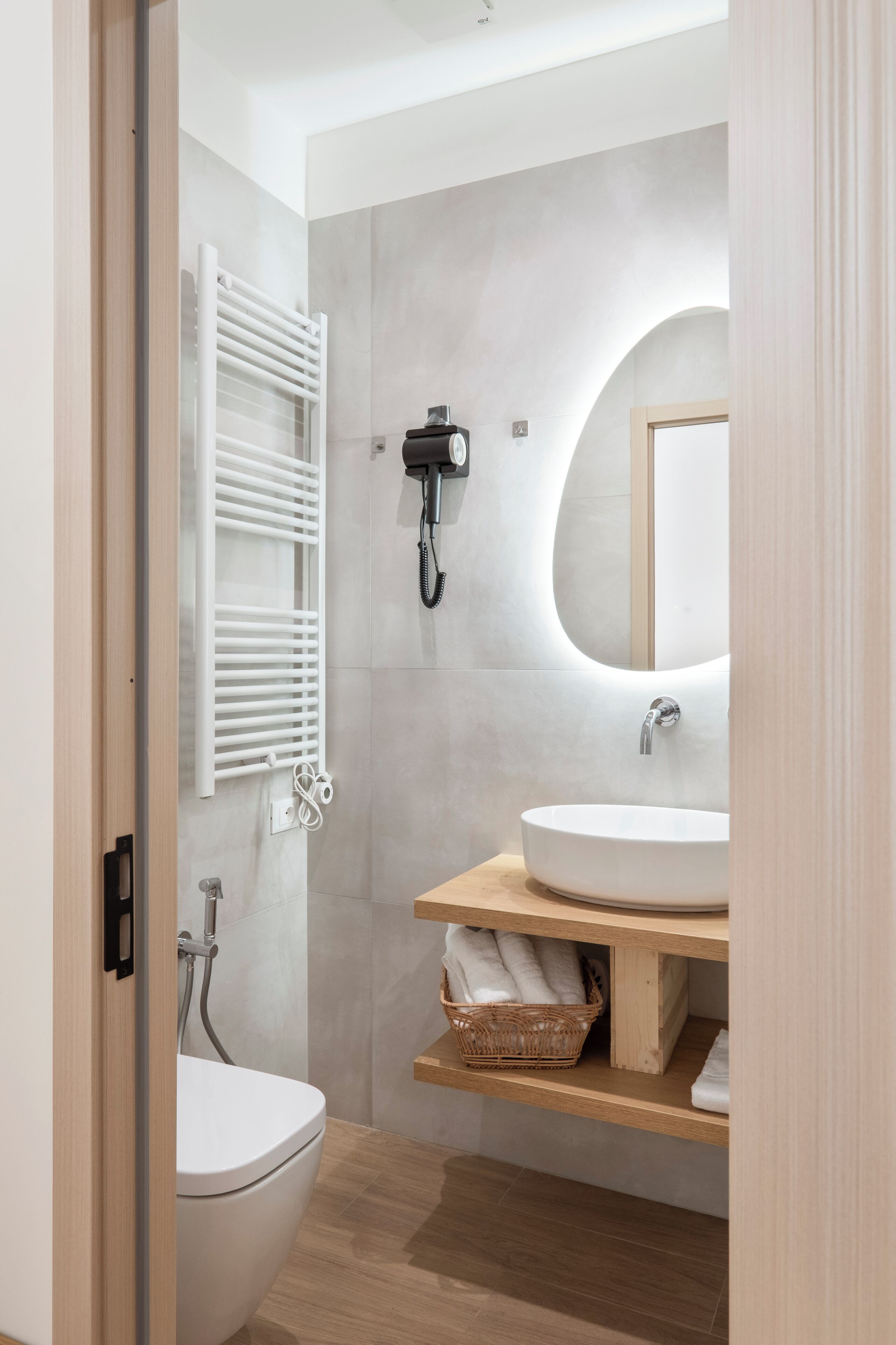 A modern bathroom with a toilet, sink, shower, and a towel rack.