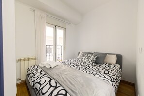 A bedroom with a bed, a radiator, a window with curtains, and a balcony. - (PRA100C) 2 bedroom and 2 bathroom apartment in the center of Madrid (Madrid)