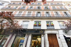 A multi-story building with a ground-floor entrance, a visible ATM, and a large wooden door. - (PRA100C) 2 bedroom and 2 bathroom apartment in the center of Madrid (Madrid)