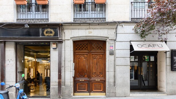 En bygning med en stor trædør og en scooter foran, med et skilt der siger 'OCAFU'.