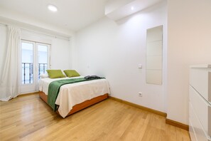 A bedroom with a bed, a window with curtains, a balcony, and a mirror on the wall. - (PRA100C) 2 bedroom and 2 bathroom apartment in the center of Madrid (Madrid)