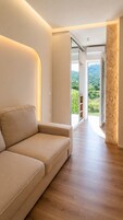Un interior moderno con sofá, suelo de madera y vistas al balcón por una puerta abierta.