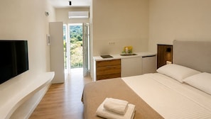 Una habitación de hotel moderna con una cama, un escritorio, un televisor y vistas al exterior.