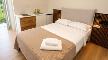 Un dormitorio moderno con cama, mesitas de noche, escritorio empotrado y vistas al exterior.
