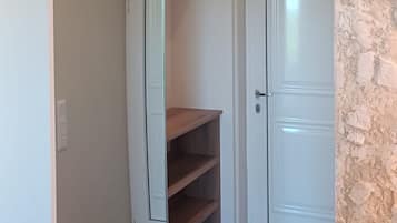 Una habitación con armario de puerta corredera, una puerta blanca y una pared de piedra.