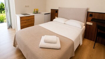 Un dormitorio con cama, mesita de noche y ventana.