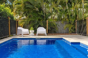 Ein Swimmingpool mit zwei weißen Liegestühlen und einem Blumentopf.