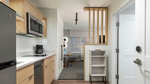 Una cocina compacta equipada con microondas, cafetera y un pequeño comedor con mesa y sillas.
