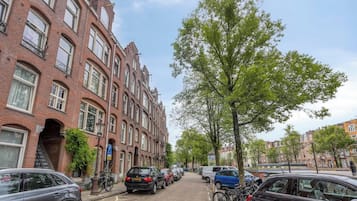 Eine Straße mit roten Backsteingebäuden, parkenden Autos und Fahrrädern.
