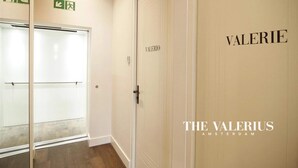 Een hal met een spiegelwand, een deur met de tekst 'VALERIO' en een nooduitgangbord.