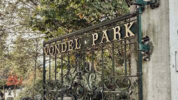 Een ijzeren poort met de tekst 'VONDEL PARK' in een park.