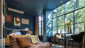Een moderne slaapkamer met een groot raam, een bed, een bank en een kleine tafel.