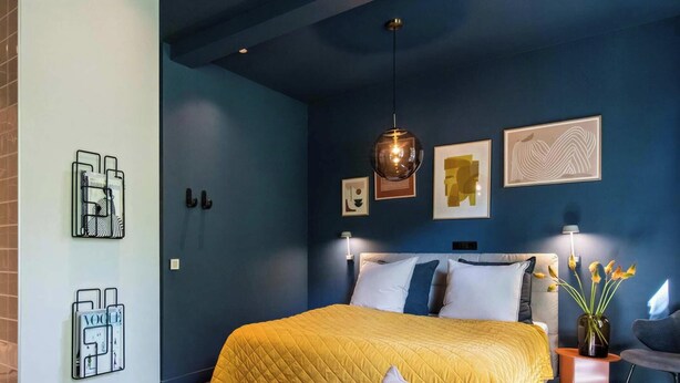 Een slaapkamer met een bed, nachtlampjes en wanddecoratie.