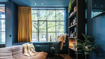 Een moderne kamer met een groot raam, een bank, een stoel en een boekenkast.