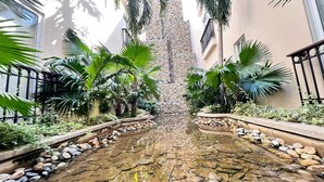 A courtyard with a water feature, palm trees, and a stone wall. - Apartment near Parque de los Novios in Santa Marta (Santa Marta)