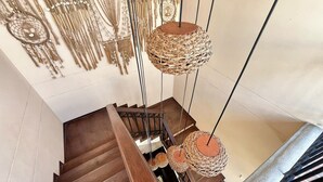 A staircase with a wooden handrail and a woven hanging light fixture. - Apartment near Parque de los Novios in Santa Marta (Santa Marta)