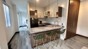 A modern kitchen with a central island, bar stools, pendant lighting, and a view of the adjacent living area. - Apartment near Parque de los Novios in Santa Marta (Santa Marta)