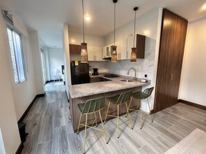 A modern kitchen with a central island, bar stools, pendant lighting, and a view of the adjacent living area. - Apartment near Parque de los Novios in Santa Marta (Santa Marta)