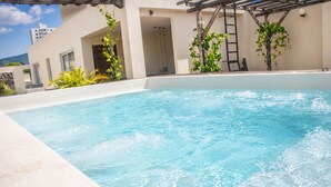 A swimming pool with clear water, surrounded by a building with a pergola and plants. - Apartment near Parque de los Novios in Santa Marta (Santa Marta)