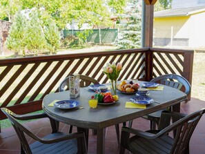 Una mesa de patio con platos azules y blancos, una jarrón y un florero con flores.