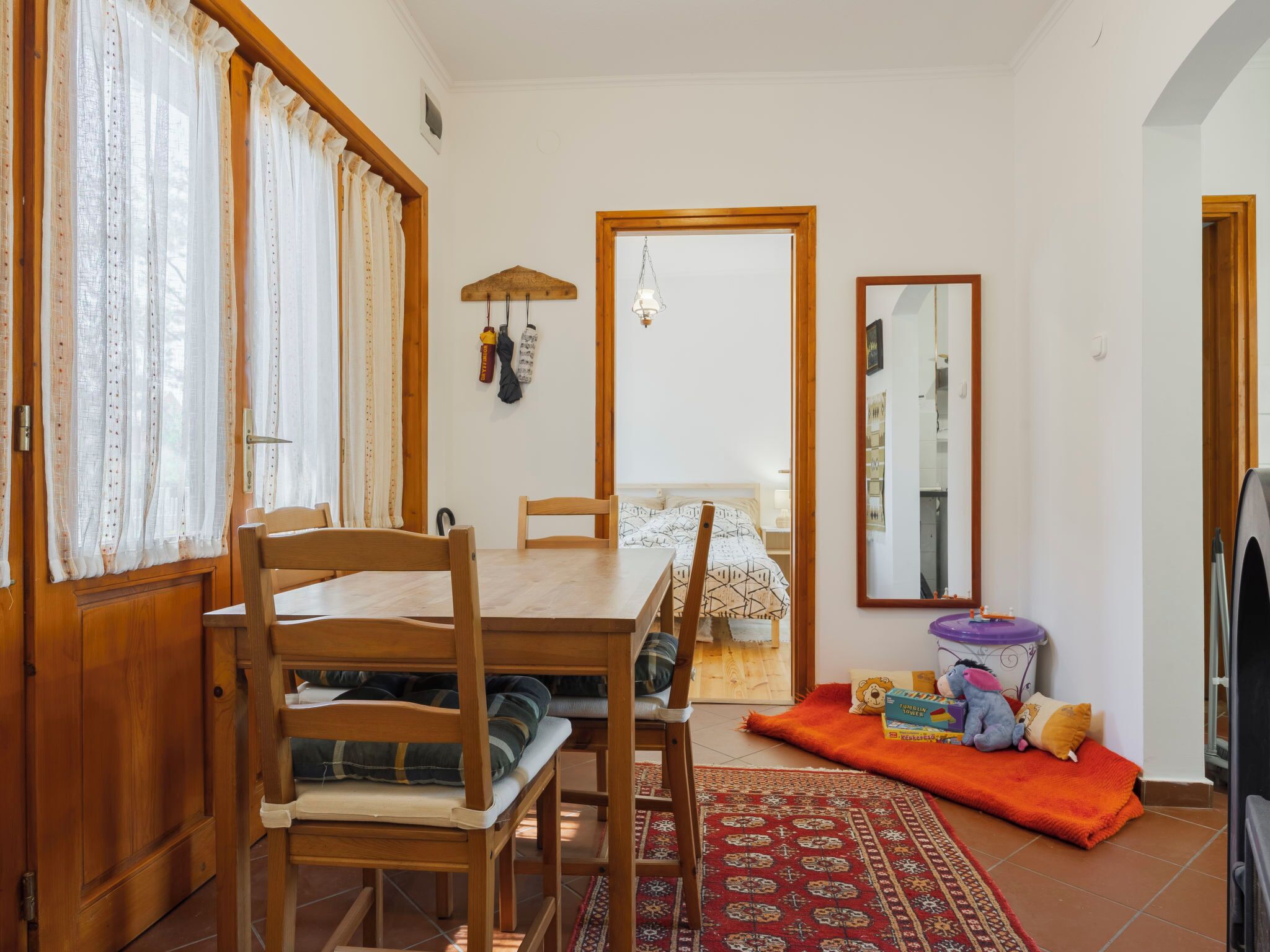 Un comedor con una mesa y sillas de madera, un tapete y una cama con edredón estampado.