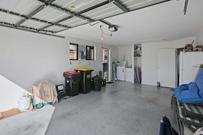 Eine Garage mit Betonboden, einer weißen Tür und einem blauen Stuhl.