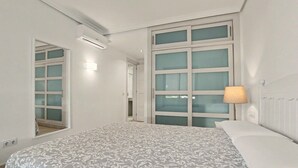 A bedroom with a large bed, a window with frosted glass, an air conditioning unit, and a radiator. - Vacation Apartment 'Balcón De Los Gigantes' with Sea View, Wi-Fi and Air Conditioning (Puerto de Santiago)