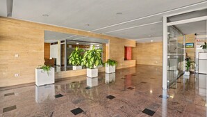 A modern lobby with a polished marble floor, wooden paneling, and potted plants. - Vacation Apartment 'Balcón De Los Gigantes' with Sea View, Wi-Fi and Air Conditioning (Puerto de Santiago)
