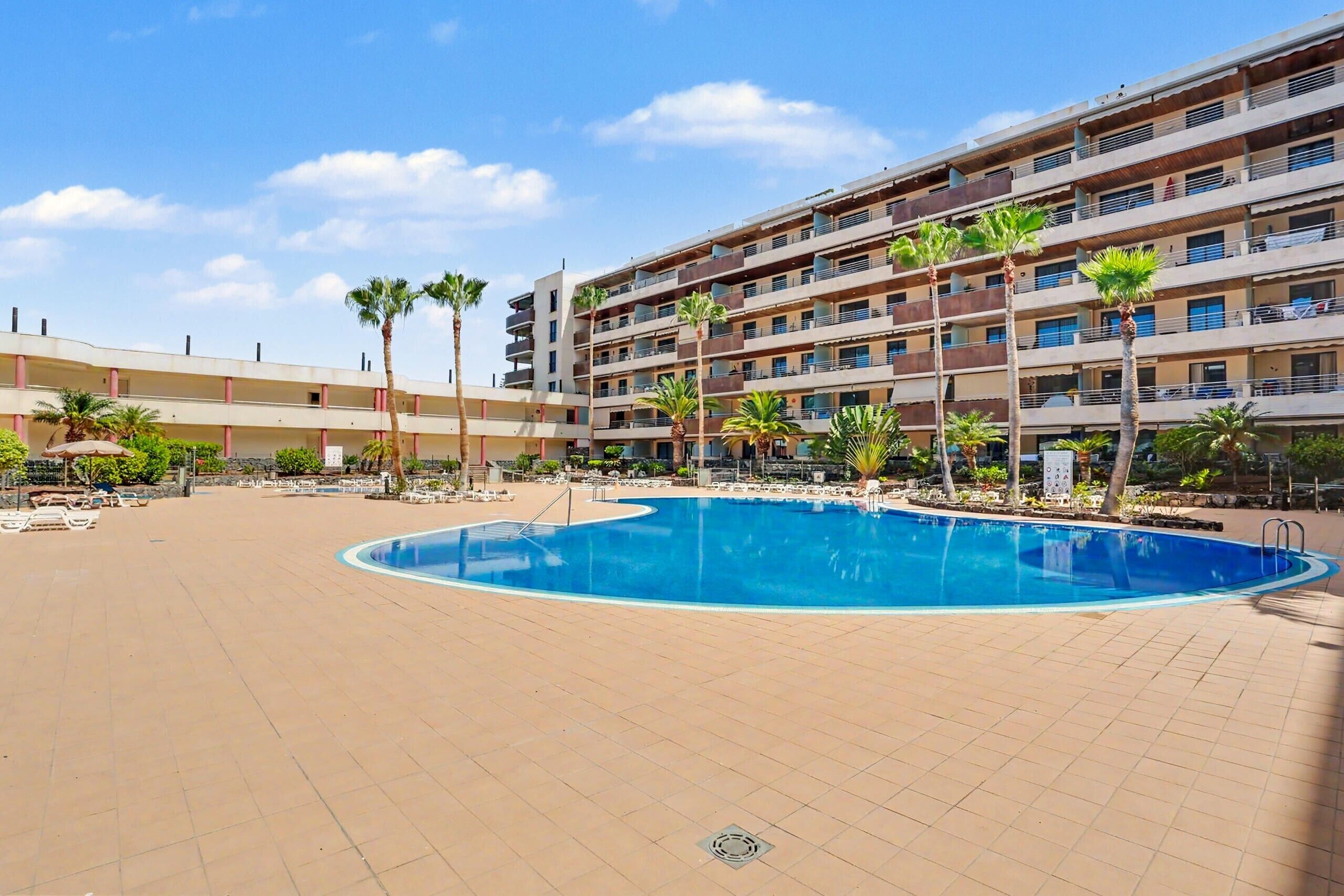 Un hôtel doté d’une piscine, de palmiers et d’un immeuble à plusieurs étages.