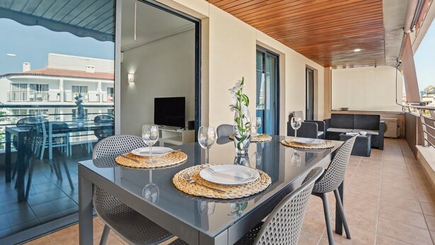 A modern dining area with a glass table, woven placemats, and a vase with flowers. - Vacation Apartment 'Balcón De Los Gigantes' with Sea View, Wi-Fi and Air Conditioning (Puerto de Santiago)