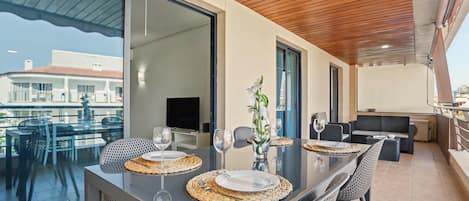 A modern dining area with a glass table, woven placemats, and a vase with flowers.
