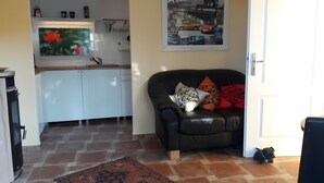 A living room with a black leather sofa, a patterned rug, and a kitchen in the background.