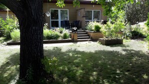 A house with a front yard, a tree, and a patio with chairs.
