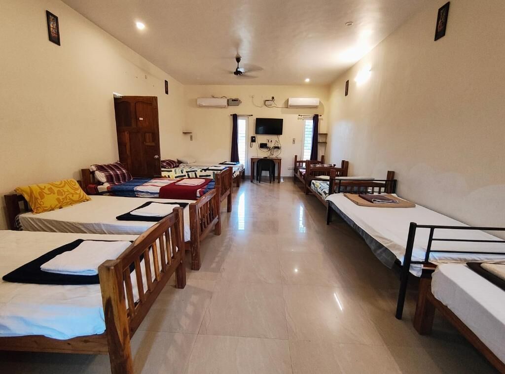 A hotel room with multiple beds, a television, and a ceiling fan.