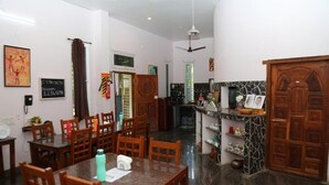 A dining area with a marble table, wooden chairs, and a kitchen in the background. - blissful haven (Vanur)