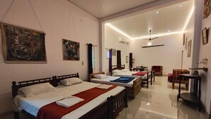 Habitación de hotel con dos camas, ventilador de techo, escritorio y una silla.