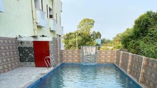 A rectangular swimming pool with a metal ladder, surrounded by a brick wall and a low concrete edge. - blissful haven (Vanur)