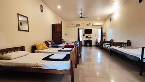 A hotel room with multiple beds, a ceiling fan, and a flat-screen TV mounted on the wall. - blissful haven (Vanur)