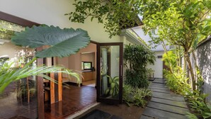 A modern interior with a wooden floor, large windows, and a view of the outdoors. - Sanga Villa by Betterplace (Pererenan)