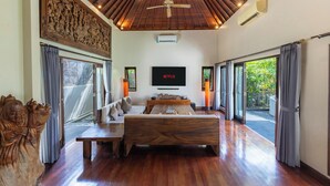 A spacious room with a wooden ceiling, a large bed, a sofa, a TV, and large windows. - Sanga Villa by Betterplace (Pererenan)