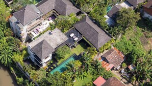 An aerial view of a residential area with multiple houses, a swimming pool, and lush greenery. - Sanga Villa by Betterplace (Pererenan)