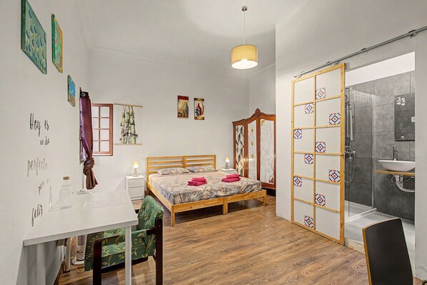 A bedroom with a wooden bed, a desk, a chair, a wardrobe, and a bathroom with a shower and sink. - Double room with private bathroom (Las Palmas de Gran Canaria)