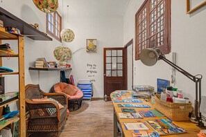 Una stanza con pavimento in legno, una scrivania con brochure di viaggio, mobili in vimini e una porta con pannello di vetro satinato.