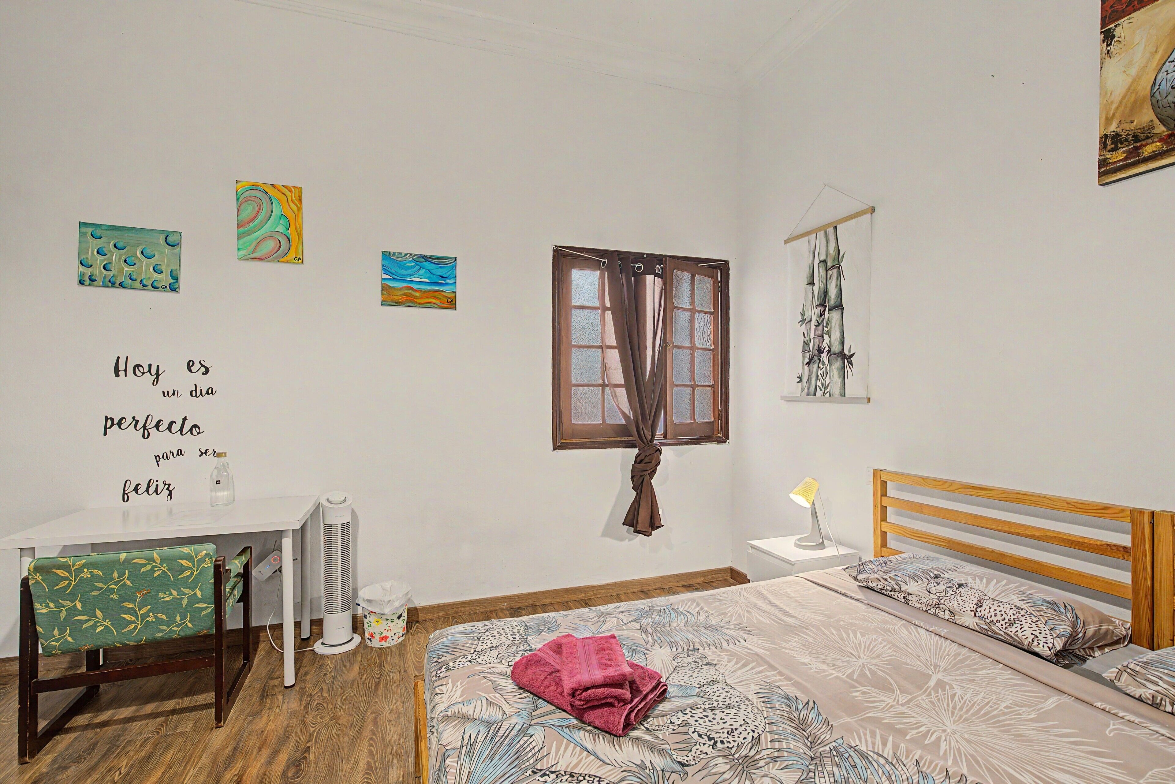 Ein Schlafzimmer mit einem Bett, einem Schreibtisch, einem Heizkörper und Wandbildern.