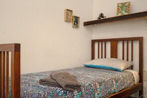 A single bed with a patterned bedspread, a folded blanket, and a pillow with a blue accent. - Triple Room with External Private Bathroom (Las Palmas de Gran Canaria)